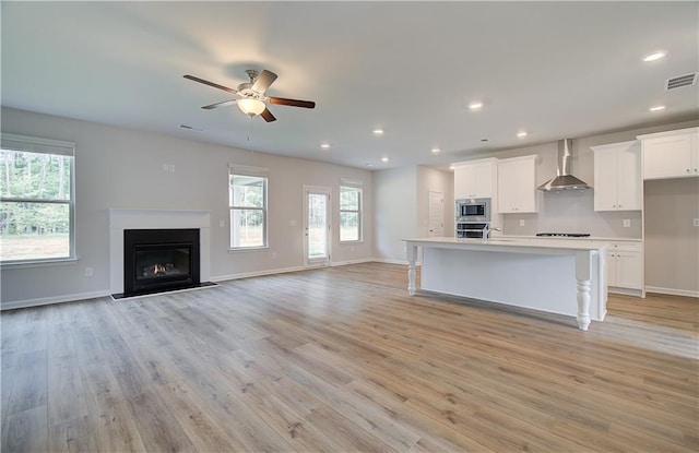 0 Cooper Cv E, Fayetteville, GA 30215 - kitchen with appliances with stainless steel finishes, wall chimney range hood, ceiling fan, white cabinets, and a fireplace with flush hearth