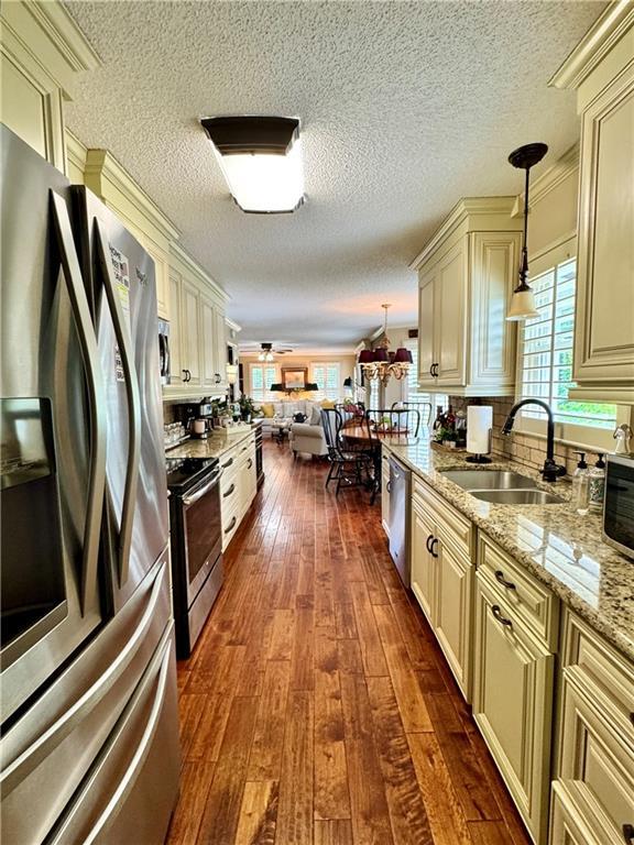 270 Owens Cir NE, Calhoun, GA 30701 - kitchen with cream cabinets, stainless steel appliances, a sink, dark wood-type flooring, and light stone counters