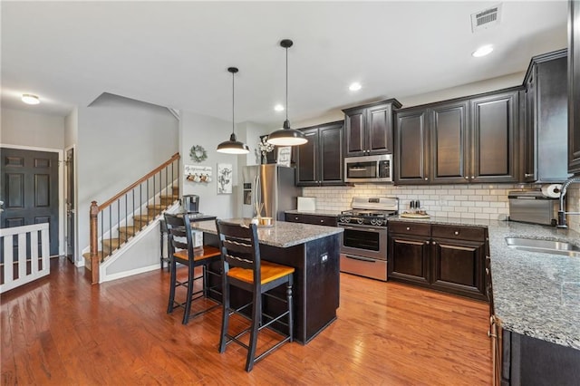 kitchen with decorative backsplash, a kitchen breakfast bar, stainless steel appliances, pendant lighting, and a kitchen island