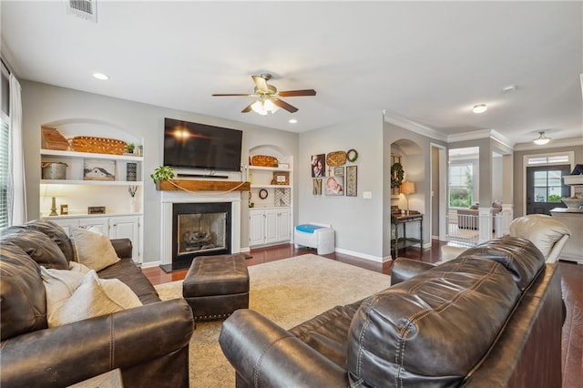 living room featuring ceiling fan, wood-type flooring, built in features, and ornamental molding