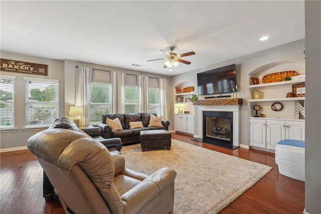 living room featuring dark hardwood / wood-style flooring, ceiling fan, and built in features