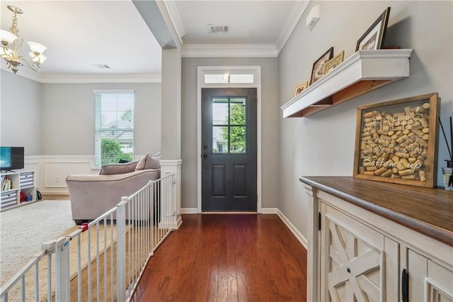 entryway with dark hardwood / wood-style flooring, ornamental molding, and a chandelier