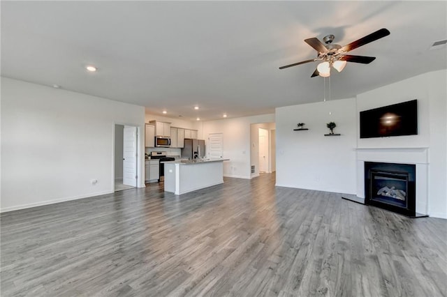82 Graham Campbell Ln, Statham, GA 30666 - unfurnished living room featuring wood finished floors, ceiling fan, a glass covered fireplace, baseboards, and recessed lighting