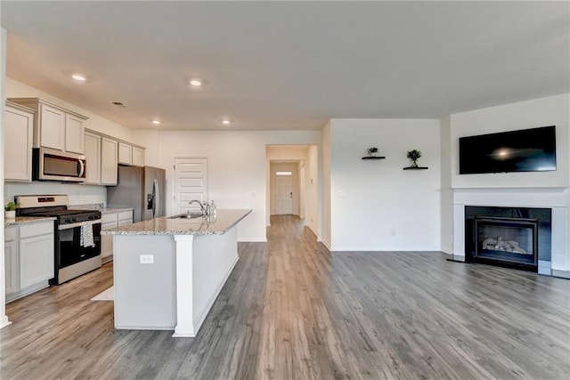 82 Graham Campbell Ln, Statham, GA 30666 - kitchen featuring appliances with stainless steel finishes, open floor plan, a center island with sink, light wood-style flooring, and a sink