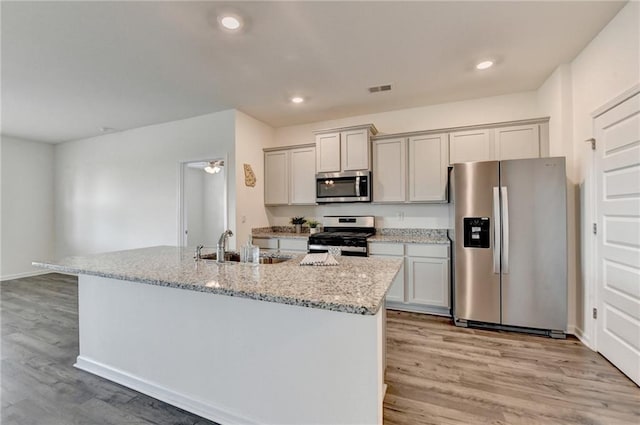 82 Graham Campbell Ln, Statham, GA 30666 - kitchen with appliances with stainless steel finishes, light wood-style floors, a sink, a center island with sink, and light stone counters