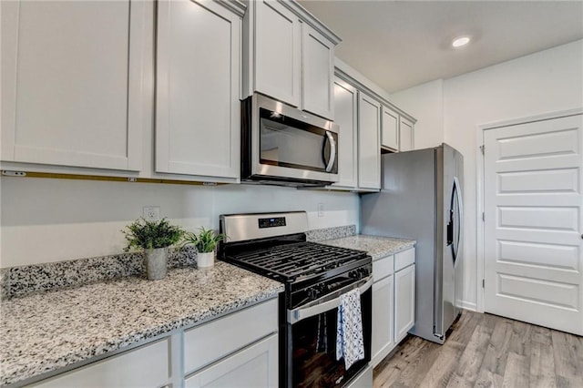 82 Graham Campbell Ln, Statham, GA 30666 - kitchen featuring appliances with stainless steel finishes, light wood-type flooring, and light stone countertops