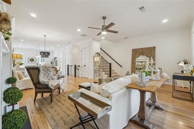 living room featuring light wood-type flooring and ceiling fan with notable chandelier