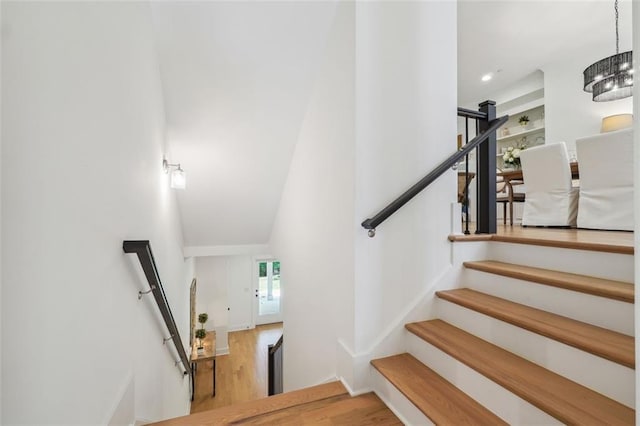 stairway with an inviting chandelier and hardwood / wood-style flooring