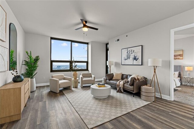 living room featuring dark wood-style flooring, visible vents, ceiling fan, and baseboards