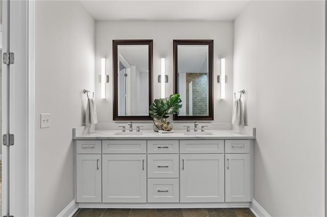 full bath featuring a sink, baseboards, and double vanity