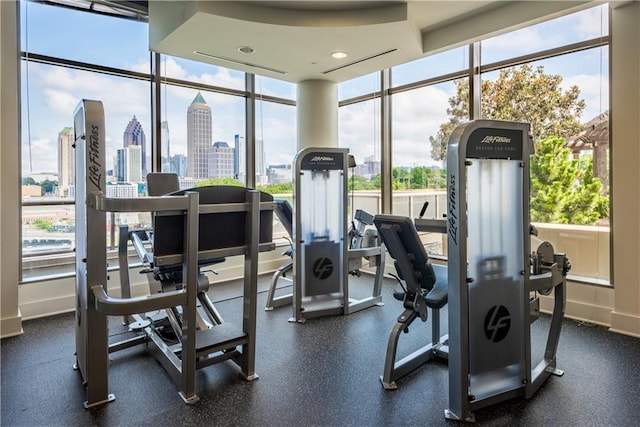 gym with a wall of windows, a view of city, and baseboards