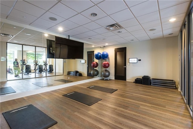 exercise area featuring wood finished floors, visible vents, and baseboards