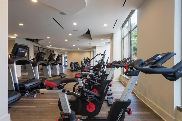 exercise room featuring baseboards, wood finished floors, and recessed lighting