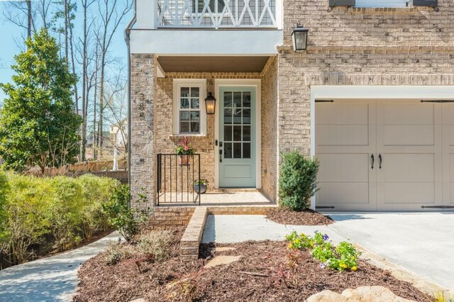 view of front of property with driveway, a balcony, a garage, brick siding, and ceiling fan