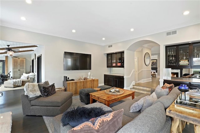 living room featuring hardwood / wood-style floors, ceiling fan, and crown molding