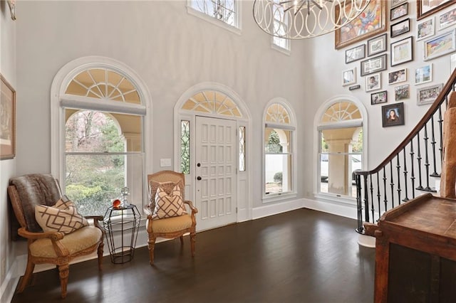 entryway featuring an inviting chandelier, dark hardwood / wood-style floors, a wealth of natural light, and a high ceiling