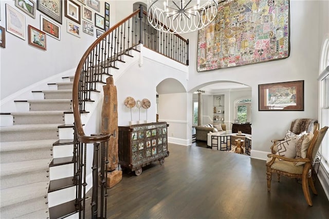 interior space featuring a towering ceiling, a notable chandelier, and dark hardwood / wood-style floors