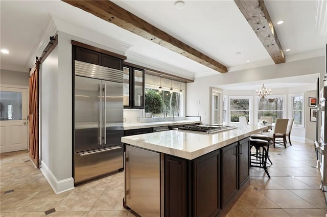 kitchen with beam ceiling, appliances with stainless steel finishes, a center island, and a wealth of natural light