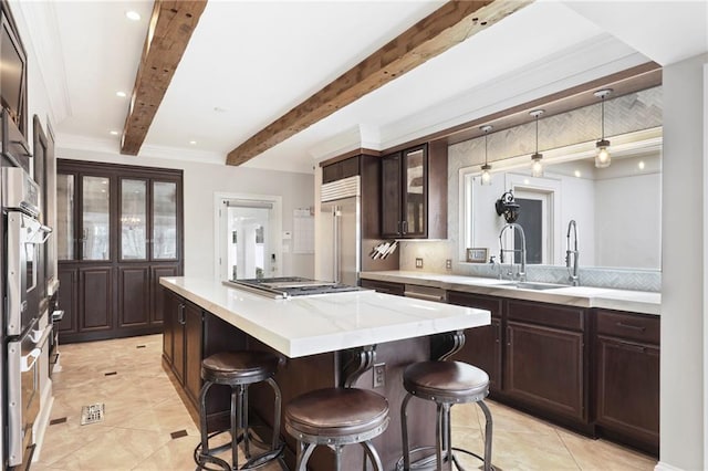 kitchen featuring beamed ceiling, a kitchen island, stainless steel appliances, a kitchen breakfast bar, and dark brown cabinets