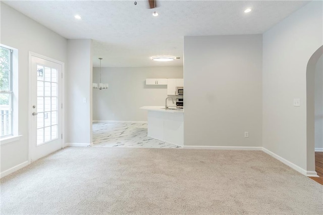 6118 Arbor Links Rd, Lithonia, GA 30058 - unfurnished living room with arched walkways, light carpet, plenty of natural light, recessed lighting, and a chandelier