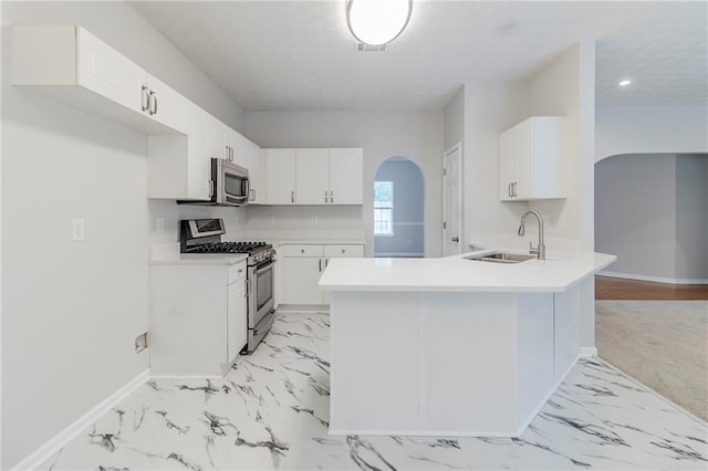6118 Arbor Links Rd, Lithonia, GA 30058 - kitchen with stainless steel appliances, light marble finish flooring, a peninsula, white cabinetry, and a textured ceiling