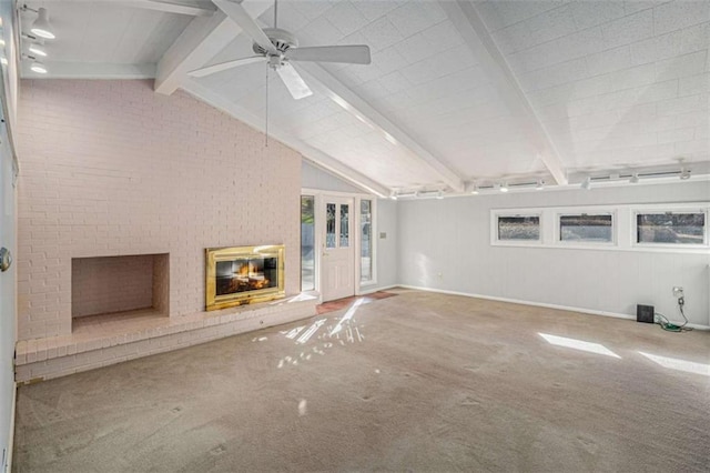 unfurnished living room with brick wall, carpet flooring, a brick fireplace, and vaulted ceiling with beams