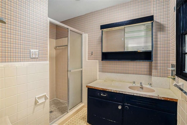 bathroom featuring tile walls, vanity, and a shower with shower door