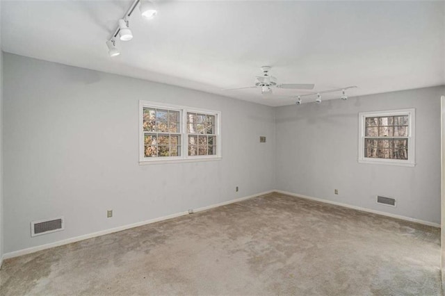 carpeted spare room featuring ceiling fan and track lighting