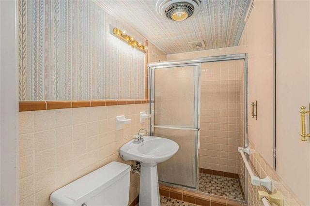 bathroom with tile walls, an enclosed shower, and toilet