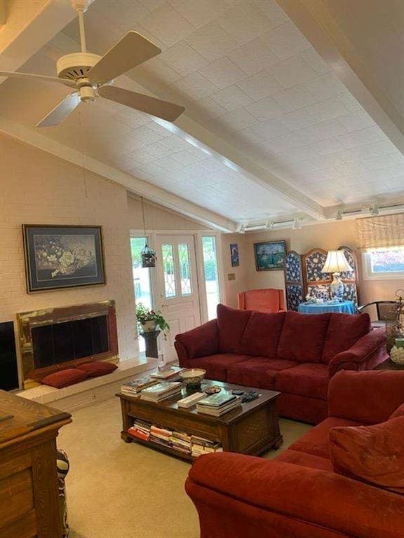 living room featuring carpet floors, a fireplace, lofted ceiling with beams, and ceiling fan