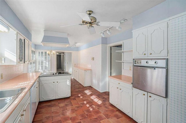 kitchen featuring white cabinetry, hanging light fixtures, black electric stovetop, oven, and ceiling fan with notable chandelier