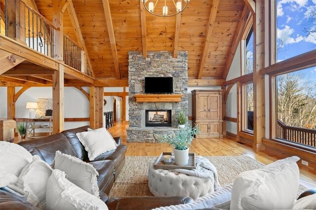 living room with a stone fireplace, wooden ceiling, high vaulted ceiling, a chandelier, and beamed ceiling