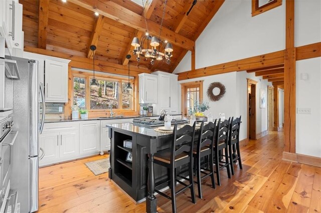 kitchen with white cabinetry, stainless steel appliances, backsplash, a center island, and beamed ceiling