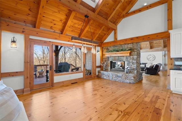 unfurnished living room with high vaulted ceiling, wooden ceiling, a fireplace, light wood-style floors, and beam ceiling