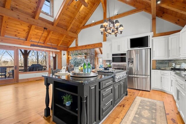 kitchen with pendant lighting, a kitchen island, dark stone countertops, stainless steel gas stovetop, and beam ceiling