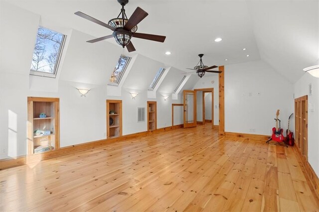 bonus room with ceiling fan, vaulted ceiling with skylight, and light hardwood / wood-style flooring