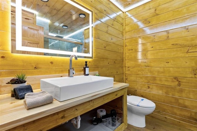 bathroom with wood ceiling, wood walls, toilet, vanity, and wood finished floors