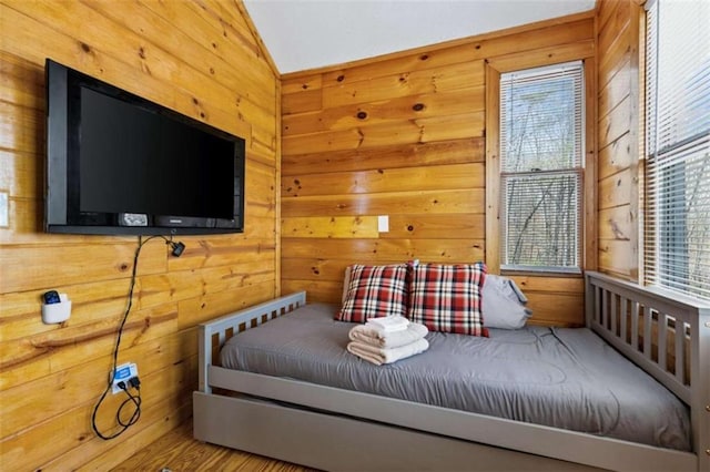 bedroom with vaulted ceiling, wooden walls, and multiple windows