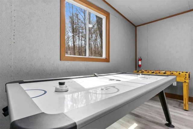 recreation room featuring a textured wall, wood finished floors, and crown molding