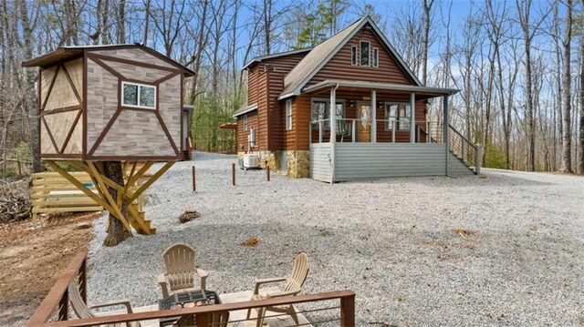rear view of house featuring faux log siding, a porch, and cooling unit