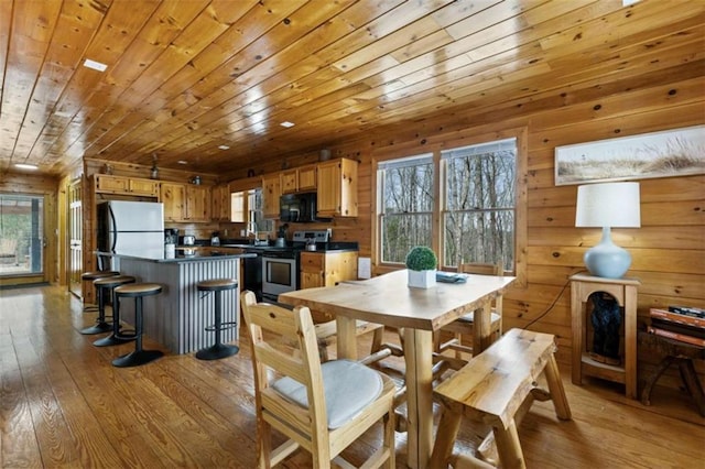 dining area with wooden ceiling, light wood finished floors, and wood walls