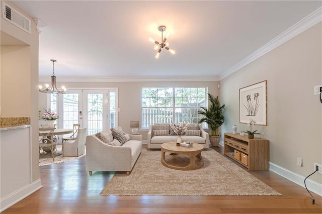 living room featuring an inviting chandelier, ornamental molding, a healthy amount of sunlight, and french doors