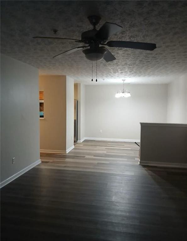 unfurnished room with dark wood-type flooring and ceiling fan with notable chandelier