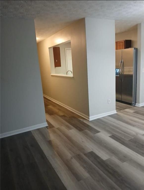 empty room with a textured ceiling and dark hardwood / wood-style flooring