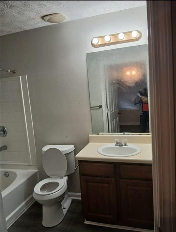 full bathroom featuring toilet, vanity, a textured ceiling, and washtub / shower combination