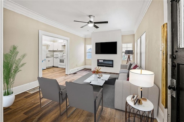 living room with crown molding, a large fireplace, ceiling fan, and hardwood / wood-style flooring