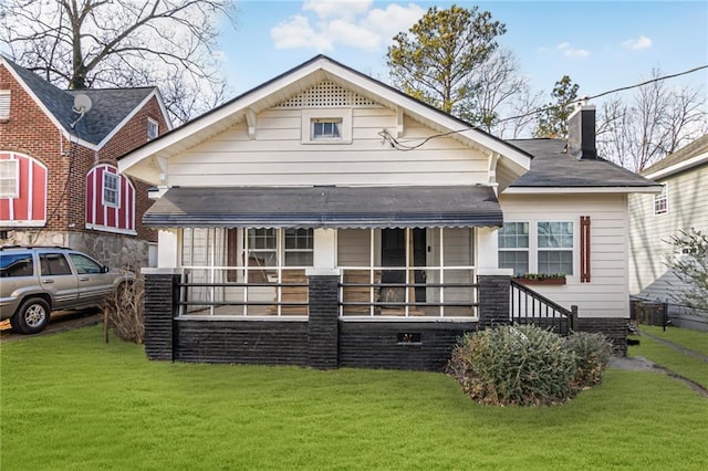 rear view of property featuring a porch and a yard