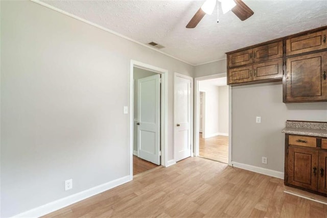 interior space with ceiling fan, light hardwood / wood-style floors, and a textured ceiling