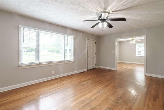 spare room featuring ceiling fan, a wealth of natural light, light hardwood / wood-style floors, and a textured ceiling