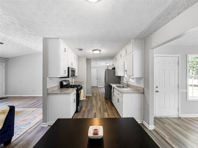 30 Court S, Ellenwood, GA 30294 - kitchen featuring appliances with stainless steel finishes, dark wood-type flooring, a textured ceiling, and white cabinets